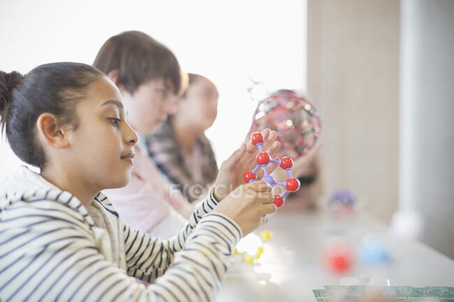Curious girl examining molecule model in classroom — Stock Photo