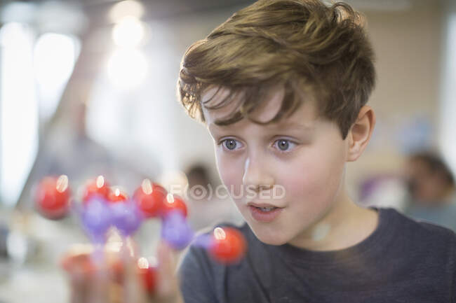 Любопытный мальчик изучает молекулярную модель в лабораторном классе — стоковое фото