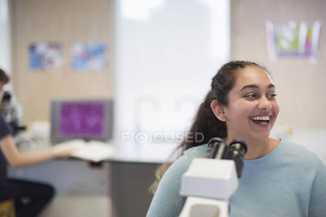 Студент сміється в мікроскопі в лабораторному класі — стокове фото