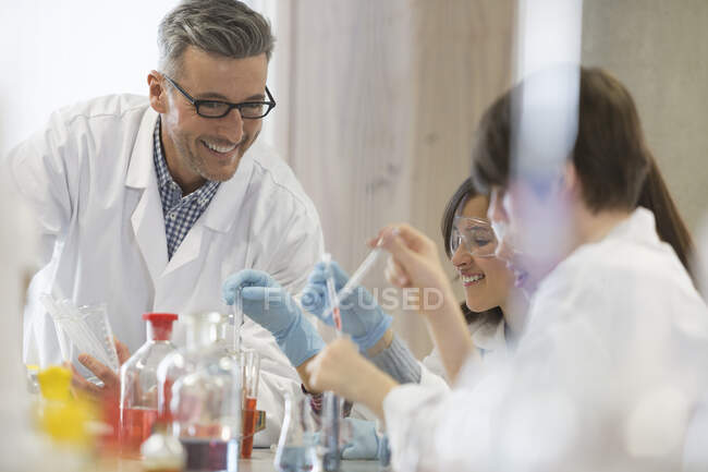 Male science teacher and students conducting scientific experiment in laboratory classroom — Stock Photo