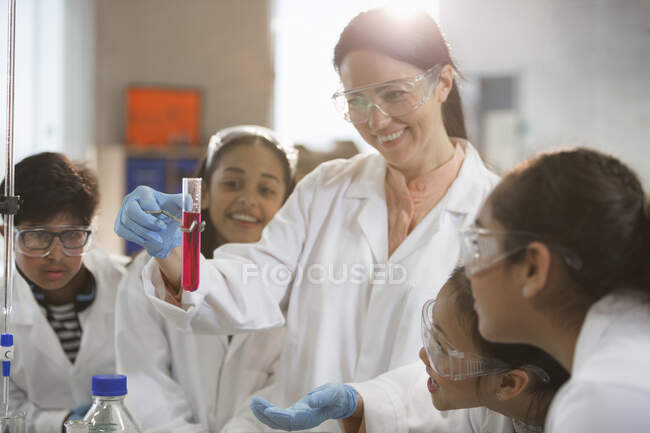 Profesora de química sonriente y estudiantes que realizan experimentos científicos en el aula de laboratorio - foto de stock