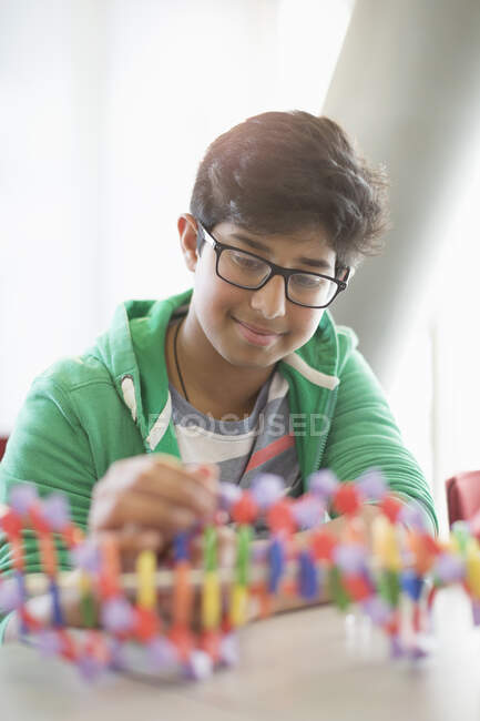 Estudiante sonriente ensamblando modelo de ADN en el aula - foto de stock