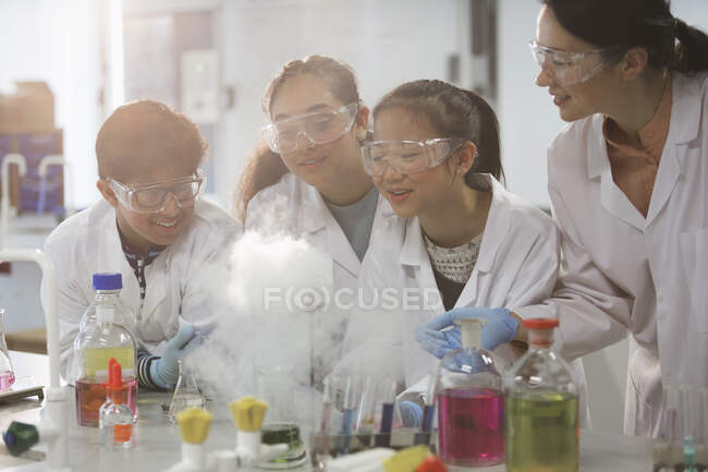 Profesora y alumnas viendo la reacción química de experimentos científicos en el aula de laboratorio - foto de stock
