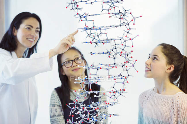 Female teacher and girl students examining molecular structure in classroom — Stock Photo