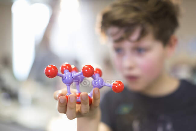 Menino estudante segurando e examinando estrutura molecular — Fotografia de Stock