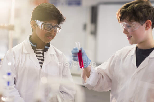 Boy students examining liquid in test tube, conducting scientific experiment in laboratory classroom — Stock Photo