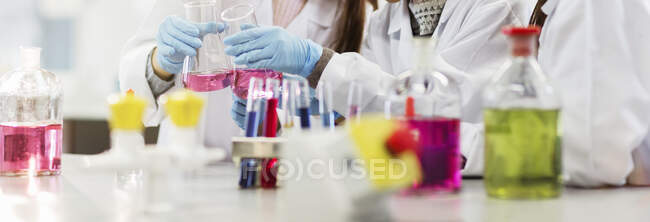 Líquido en botellas, tubos de ensayo y vasos de precipitados en el aula de laboratorio científico - foto de stock