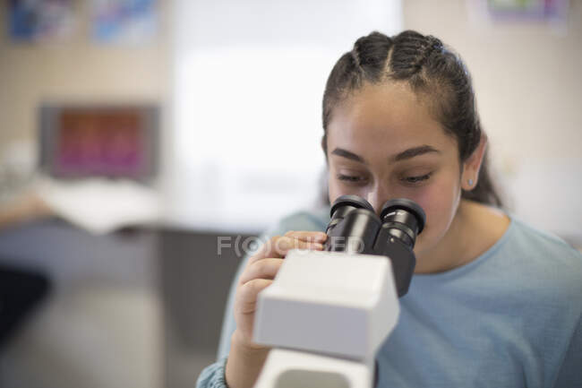 Menina estudante usando microscópio em sala de aula — Fotografia de Stock