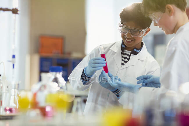 Meninos estudantes conduzindo experimentos científicos, examinando líquido em tubo de ensaio em sala de aula de laboratório — Fotografia de Stock