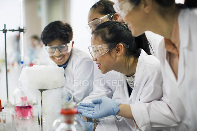 Curious students watching chemical reaction, conducting scientific experiment in laboratory classroom — Stock Photo