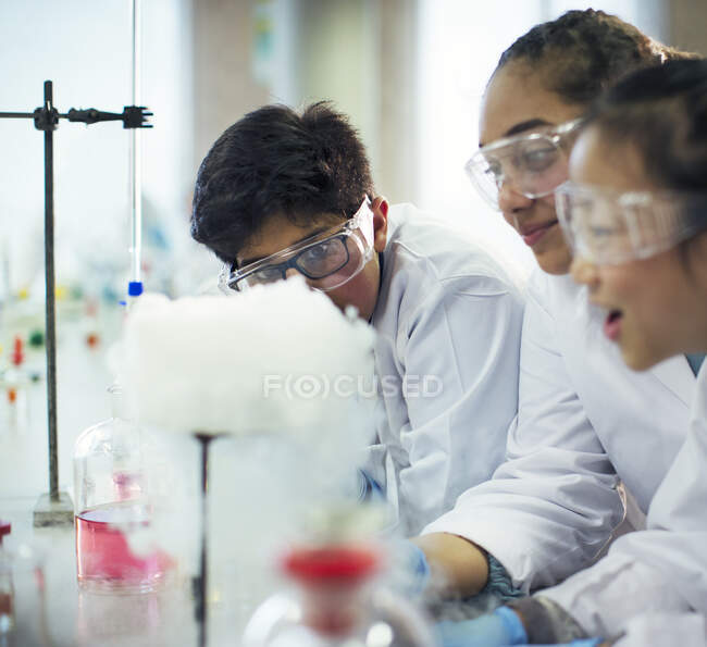 Students watching chemical reaction, conducting scientific experiment in laboratory classroom — Stock Photo