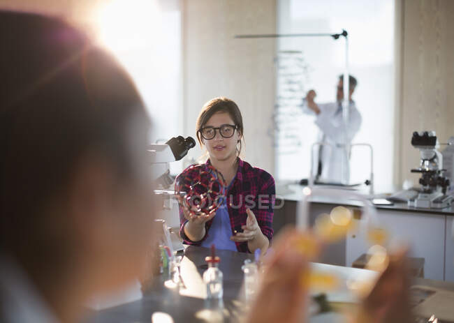 Menina estudante segurando estrutura molecular ao microscópio em sala de aula de laboratório — Fotografia de Stock