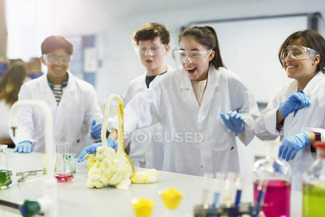 Estudiantes sorprendidos llevando a cabo un experimento científico de espuma explosiva en el laboratorio del aula - foto de stock