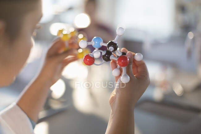 Curious girl student holding molecule model in classroom — Stock Photo