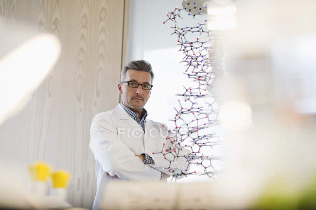 Porträt selbstbewusster, seriöser männlicher Naturwissenschaftsprofessor, der im Klassenzimmer hinter der molekularen Struktur steht — Stockfoto