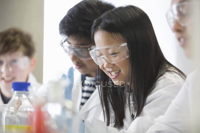 Chica sonriente llevando a cabo un experimento científico en el aula de laboratorio - foto de stock