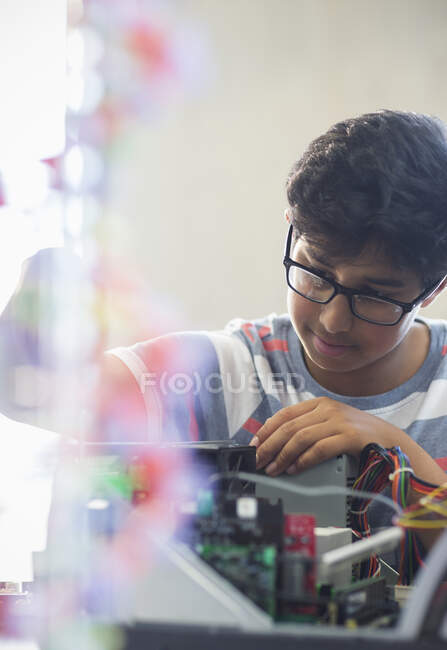 Enfocado niño estudiante montaje de computadoras en el aula - foto de stock