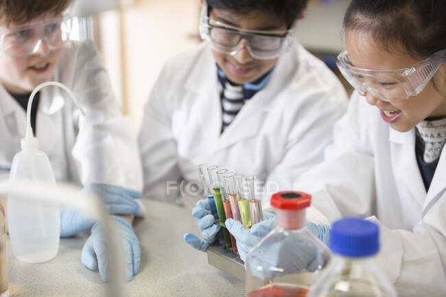Studenti che esaminano liquidi in provetta rack, condurre esperimenti scientifici in classe di laboratorio — Foto stock