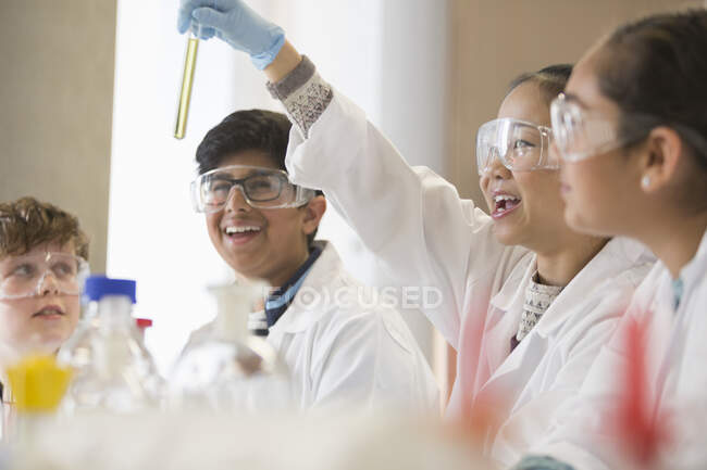 Estudiantes examinando líquido en probeta, realizando experimento científico en aula de laboratorio - foto de stock