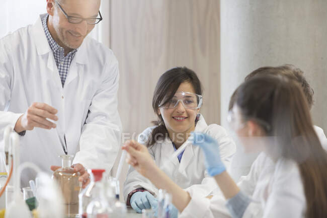 Insegnante maschio e studenti che conducono esperimenti scientifici in classe di laboratorio — Foto stock