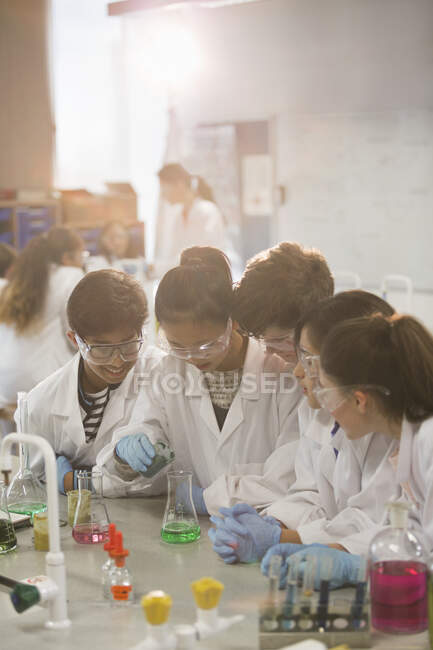 Students conducting scientific experiment, pouring liquid in beaker in laboratory classroom — Stock Photo