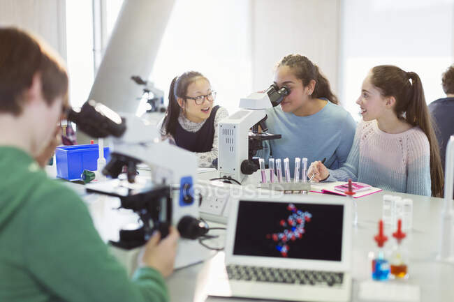 Girl students using microscope, conducting scientific experiment in laboratory classroom — Stock Photo