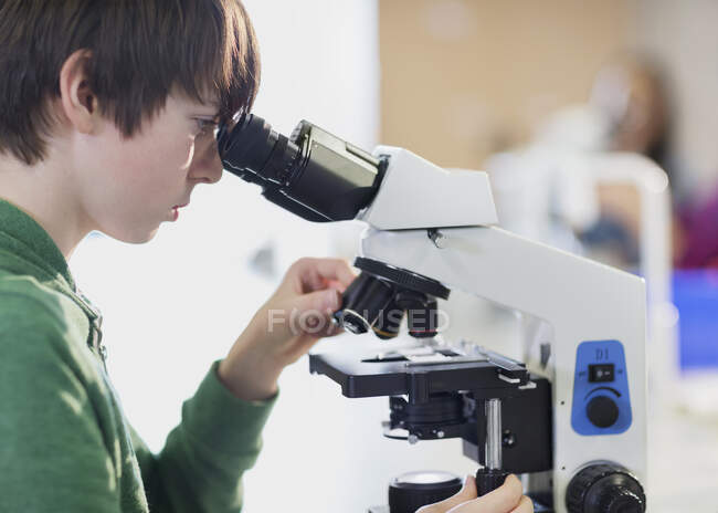 Студент-орієнтований хлопець використовує мікроскоп у класі — стокове фото