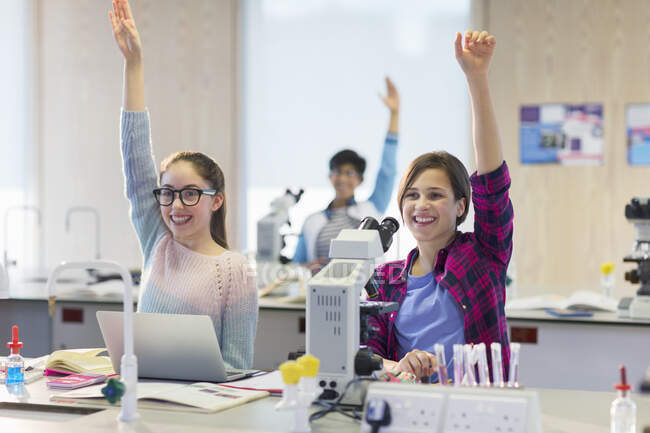 Eager, smiling students raising hands in science laboratory classroom — Stock Photo