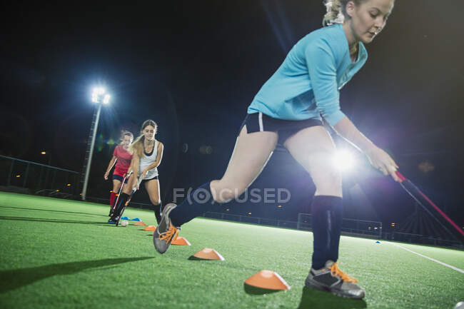 Jóvenes jugadoras de hockey sobre hierba practicando ejercicios deportivos en el campo - foto de stock