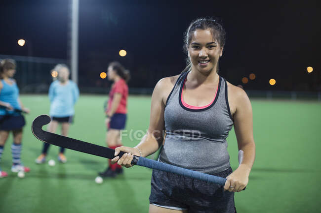 Retrato confiante jogador de hóquei em campo feminino segurando vara de hóquei em campo — Fotografia de Stock
