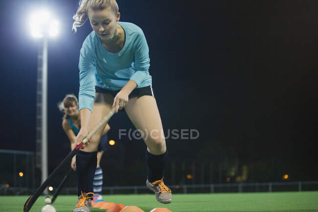 Joven jugadora de hockey sobre césped enfocada a practicar ejercicio deportivo en el campo - foto de stock