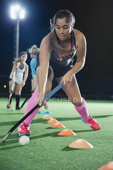 Focused young female field hockey player practicing sports drill on field — Stock Photo