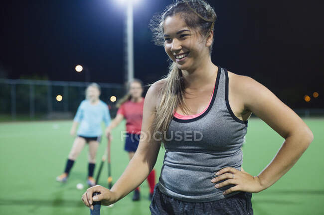 Sorrindo jovem jogadora de hóquei em campo no campo — Fotografia de Stock