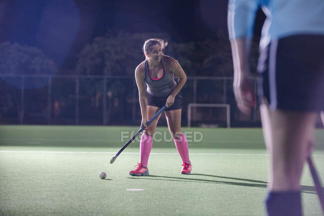 Female field hockey player hitting the ball with hockey stick on field — Stock Photo