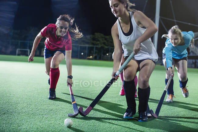 Giovani giocatori di hockey su prato femminile che corrono a palla, giocare a hockey su prato sul campo di notte — Foto stock