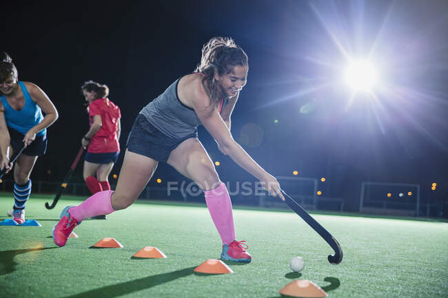 Determinato giovane giocatore di hockey su prato femminile praticare esercitazione sportiva sul campo di notte — Foto stock