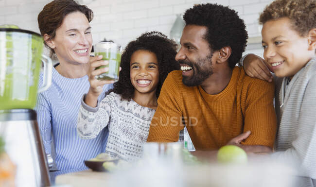 Smiling multi-ethnic family drinking healthy green smoothie in kitchen — Stock Photo