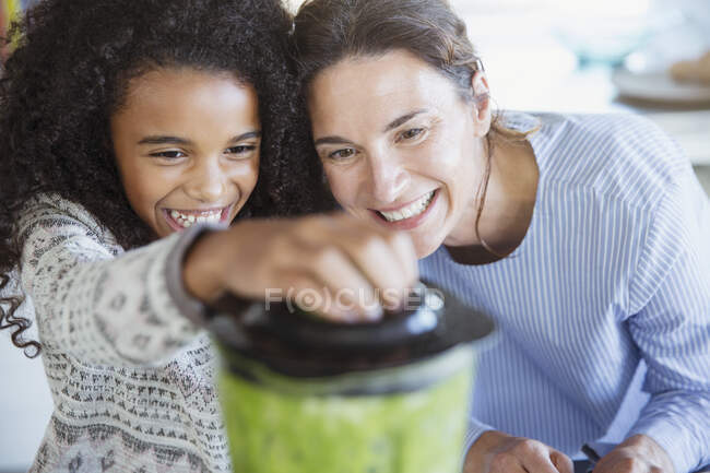 Mère et fille faisant smoothie vert sain dans le mélangeur — Photo de stock