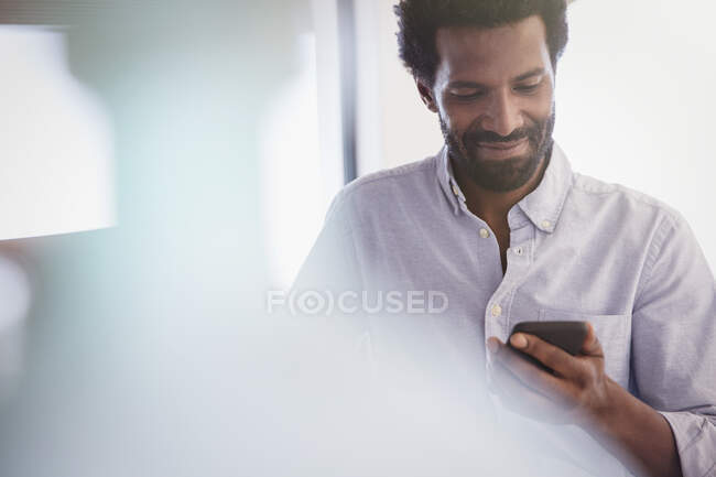 Hombre sonriente mensajes de texto con teléfono celular - foto de stock