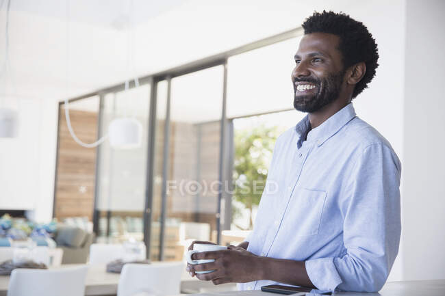 Un homme souriant buvant du café, détournant les yeux — Photo de stock
