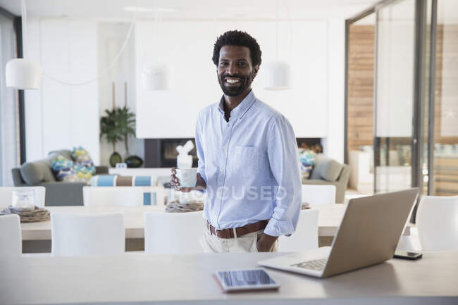Retrato sorridente empresário beber café no laptop na cozinha — Fotografia de Stock