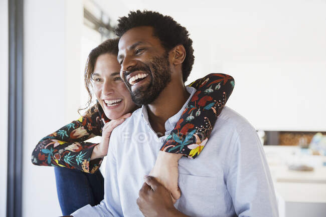 Rire, couple affectueux multi-ethnique détournant les yeux — Photo de stock