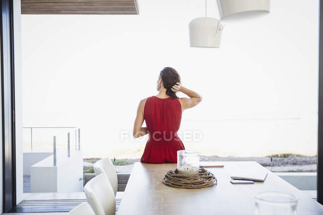 Femme brune avec les mains dans les cheveux regardant la fenêtre du patio — Photo de stock