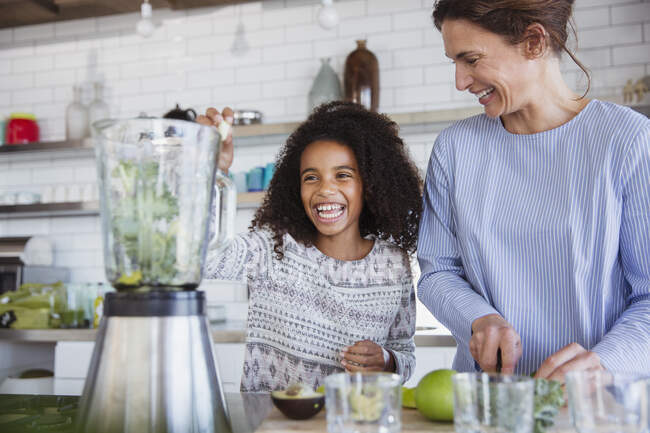 Мати і дочка роблять здорову зелену смужку в блендері на кухні — стокове фото