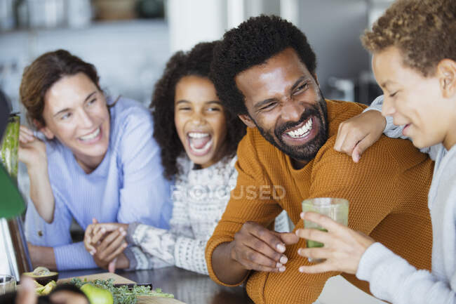 Família rindo bebendo smoothie verde saudável na cozinha — Fotografia de Stock