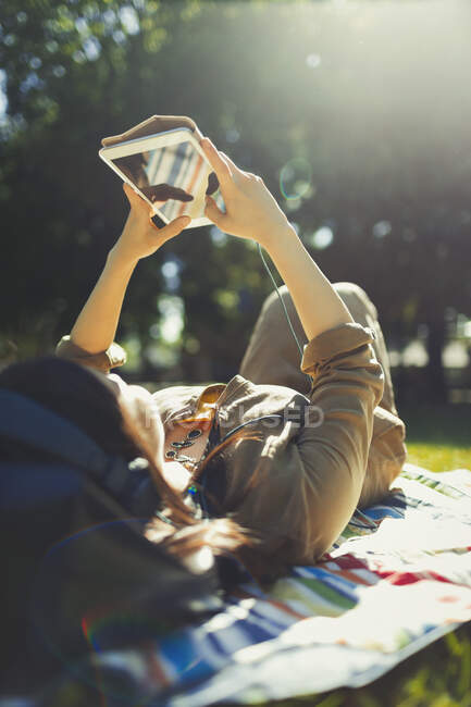 Giovane donna rilassante e utilizzando tablet digitale nel soleggiato parco estivo — Foto stock