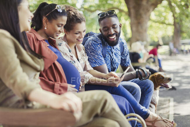 Amici sorridenti con tablet digitale sulla panchina del parco — Foto stock
