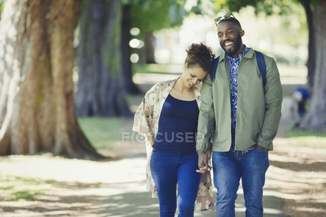 Молода пара тримає руки, ходить в парку — стокове фото