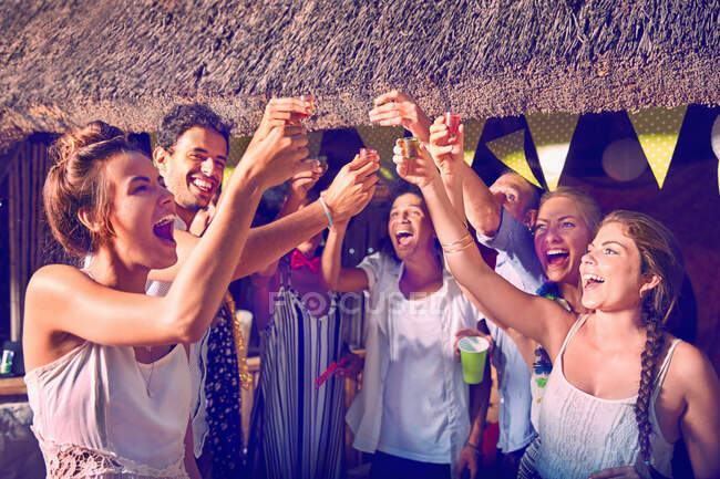 Jóvenes amigos celebrando beber vasos de alcohol en la fiesta - foto de stock
