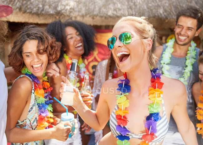 Amis ludiques portant leis boire et faire la fête au bord de la piscine ensoleillée d'été — Photo de stock